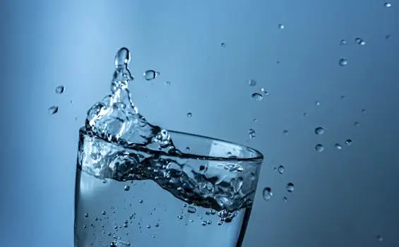 A dynamic splash of water in a clear glass against a blue background.
